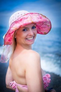 Portrait of smiling young woman against pink sea