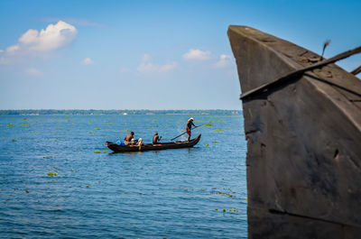 People on boat sailing in sea against sky