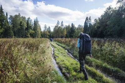 Rear view of woman with backpack walking on grassy field