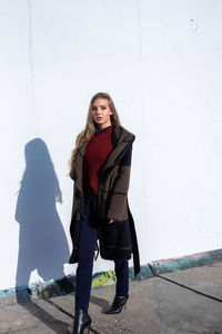 Full length portrait of woman standing against wall