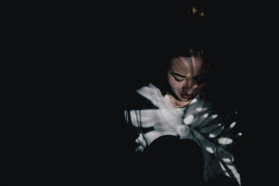 Dark conceptual mystic portrait of young girl with projector lighting against black background