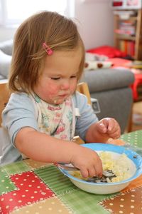 Cute girl eating food on table at home