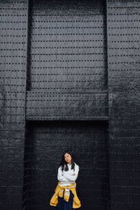 Portrait of woman standing against wall