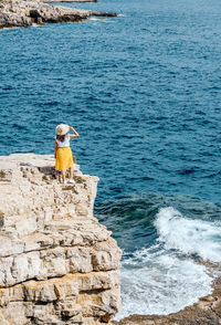 Young woman in summer clothes and hat on cliffs above sea. waves, nature, summer, travel.