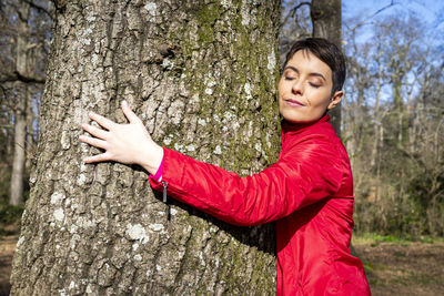 Young woman hugs a large oak tree. the woman closes and perceives the energy of nature.