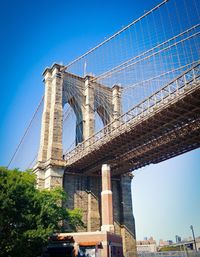 Low angle view of suspension bridge against blue sky