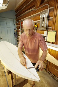 Man preparing surfboard while working in workshop