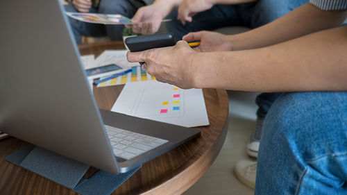 Midsection of man using mobile phone on table