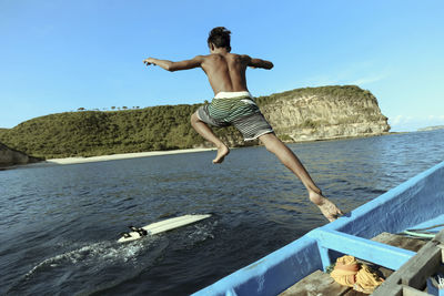 Asian surfer jumping into sea