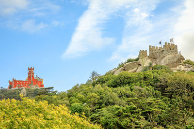 Low angle view of historic building on mountain against clear blue sky during sunny day