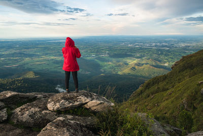 Rear view of woman standing on rock against sky