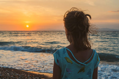 Rear view of woman looking at sea during sunset