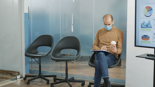 Man filling form while sitting on chair