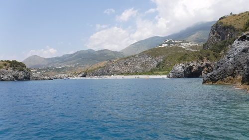 Scenic view of sea by mountains against sky