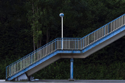 Footbridge over street against trees