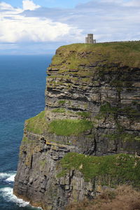 Scenic view of cliff by sea against sky