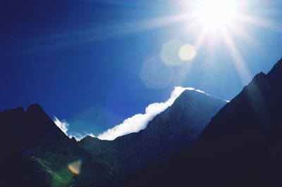 Low angle view of sun shining over mountain