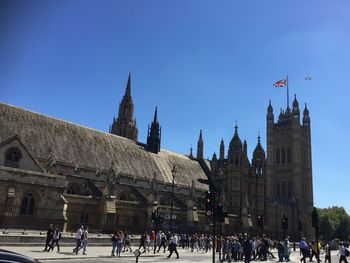 Tourists on top of historic building against blue sky