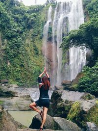 Full length of woman exercising near waterfall