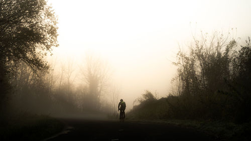 Man walking on road against sky during foggy weather