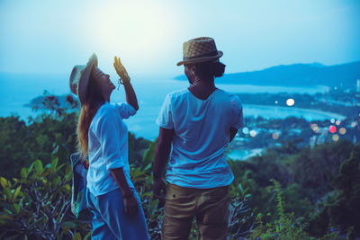 Happy couple looking at sea while standing on mountain