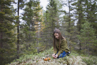 Girl kneeling in forest