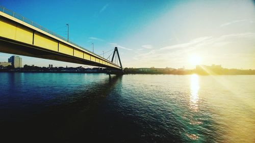 View of suspension bridge over river at sunset