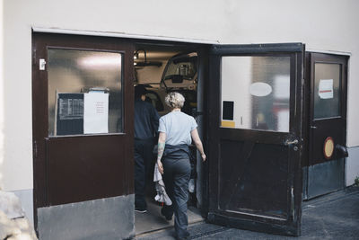 Rear view of female mechanics entering auto repair shop