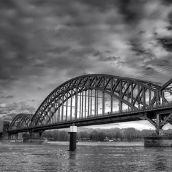 Bridge over river against cloudy sky