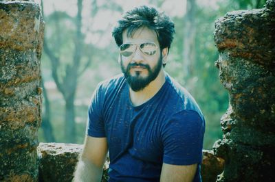 Portrait of man wearing sunglasses standing against trees