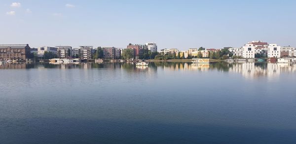 Buildings by lake against sky in city