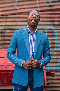 Portrait of a young businessman standing against corrugated iron