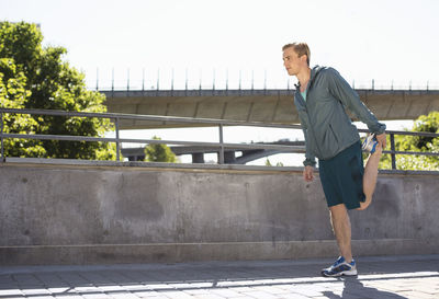 Full length of man doing stretching exercise on bridge