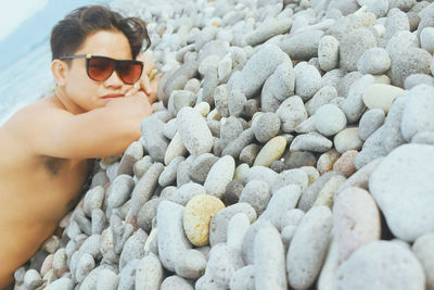 Young woman wearing sunglasses and pebbles at beach