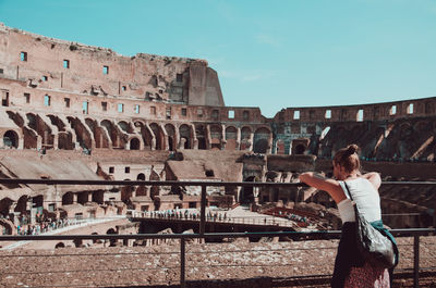 Woman standing at historical building against sky