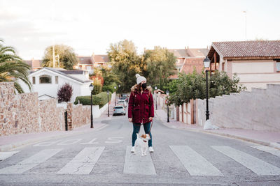 Woman with dog standing on road against sky