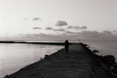 Silhouette man standing on beach against sky