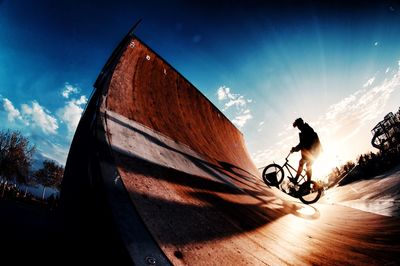 Man riding bicycle on street against sky