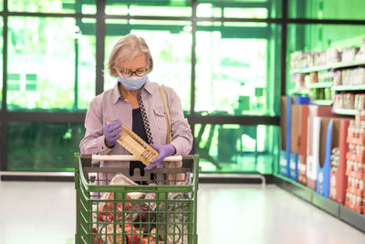 Senior woman wearing flu mask standing in store