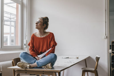 Young woman sitting on table thinking