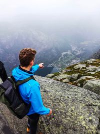 Man pointing while standing on rock