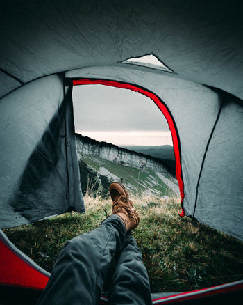 Low section of man relaxing in tent on mountain
