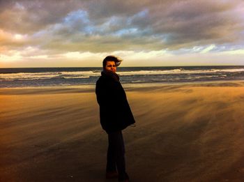 Full length of man standing on beach during sunset