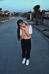 Portrait of young woman standing on road