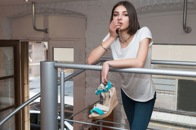 Portrait of beautiful woman standing by railing