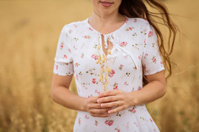 Unrecognizable woman in white idi dress walking across the field