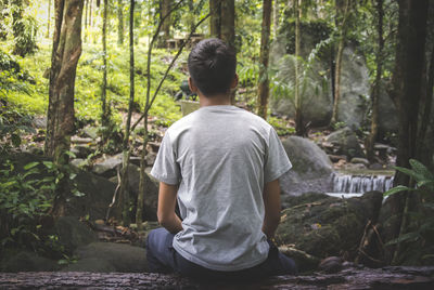 Rear view of man sitting in forest