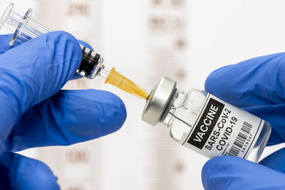 Cropped hands of person inserting syringe in vial