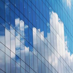 Full frame shot of modern glass building against blue sky