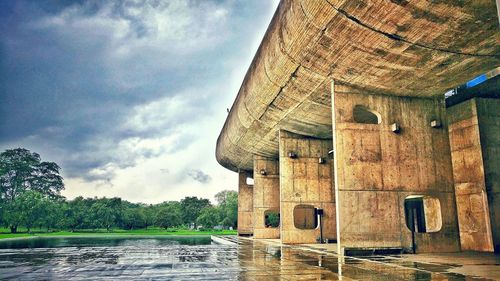 Built structure in front of river against cloudy sky